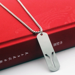 Macro view of a stainless steel rectangular pendant with a cutout letter Y on a red book