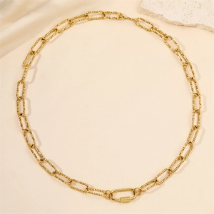 Collier à maillons trombone dorés avec fermoir mousqueton texturé sur fond de marbre