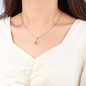 Collier Balance doré avec pendentif zodiaque en zircons porté sur un mannequin en haut blanc
