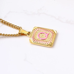 Detail van de vierkante hanger met roze emaille letter Q aan een 18k gouden cubaanse ketting