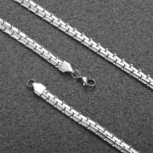 Close-up of silver flat Cuban link necklace with lobster clasp on textured grey background