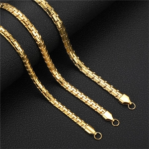 Macro detail of three glossy golden flat embossed Cuban necklaces on black leather