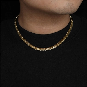 Detail of golden cylindrical link necklace worn by male model on black background
