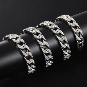 Detail of silver iced-out Cuban link bracelets with sparkling rhinestones on black stand