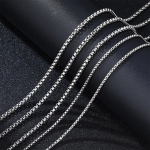 Vista macro de collares de cadena de caja en acero inoxidable plata sobre base negra