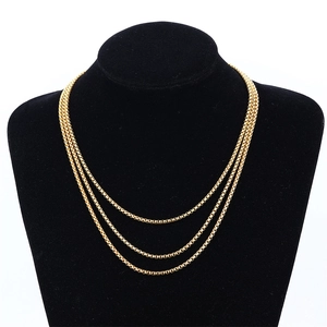 Conjunto de collares de tres capas con cadena de caja dorada en un busto negro