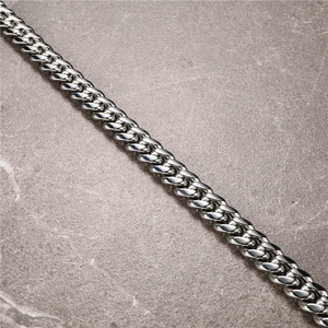 Mens thick Cuban link chain bracelet in polished stainless steel on marble background