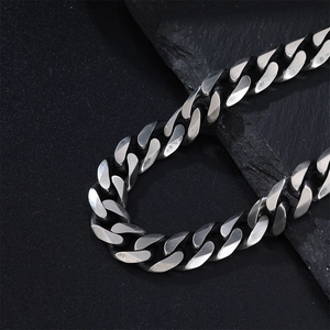 Close-up of matte silver Cuban link chain with brushed steel texture on dark rock