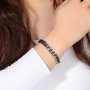 Close-up of a rugged stainless steel Cuban link bracelet on a wrist with striped shirt