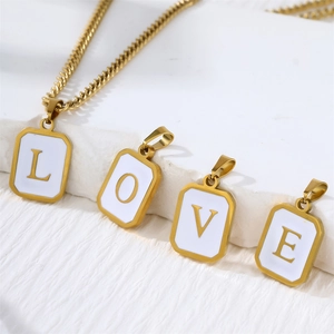 Close-up of square stainless steel gold pendants with letters L, O, V, E on shell base