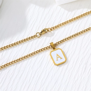 Macro detail of golden letter A square pendant on stainless steel curb chain with lobster clasp