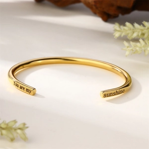 Détail macro du bracelet jonc C en or 18k avec message gravé 'You are my sunshine'