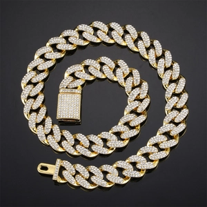 Iced out gold Cuban link chain necklace with sparkling crystals on black mirror surface