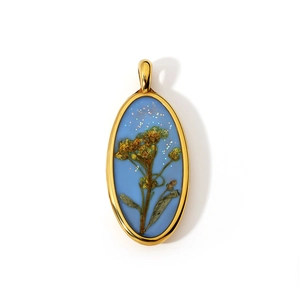 Ovale gouden hanger met echte gedroogde bloemen en blauwe glitterhars op wit oppervlak