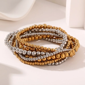 Dettaglio dei bracciali multistrato a sfere elastiche in acciaio placcato oro 18K e argento