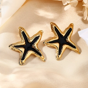 Primer plano de pendientes de estrella de mar en esmalte negro y metal dorado