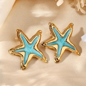 Detalle de pendientes de estrella de mar irregulares bañados en oro con esmalte azul