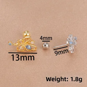 Detailed macro view of blue zircon butterfly cartilage stud earrings in gold and silver