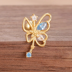 Macro detail of gold butterfly cartilage piercing with blue zircon and screw back closure