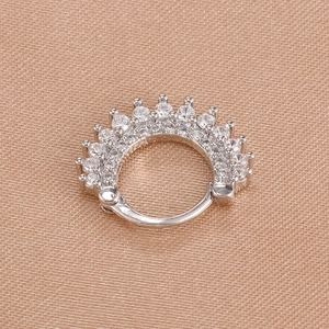 Macro shot of sparkling silver crown earrings with inlaid cubic zirconia on silk fabric
