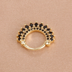 Detail of gold crown earrings with micro-paved black zircons on silk background