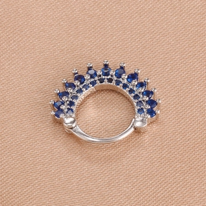 Macro shot of silver clicker earring with dark blue round gemstones in a crown design