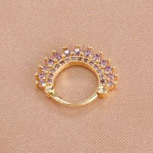 Macro shot of gold hoop earrings with gradient purple crystals on textured silk