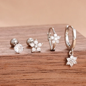 Close-up of four-piece silver flower earrings set with clear zircon on wood stand
