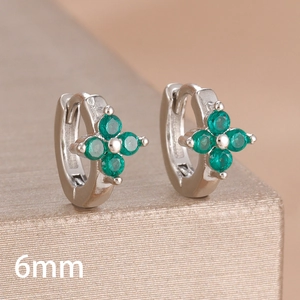 Macro shot of 6mm silver clover hoop earrings with green zircons on a gold metal stand