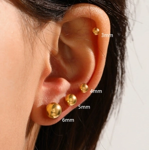 Classic golden ball stud earrings in 3mm to 6mm sizes shown on ear model