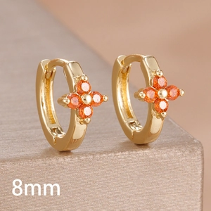 Close-up of 8mm gold huggie earrings with orange zircon four-leaf clover detail
