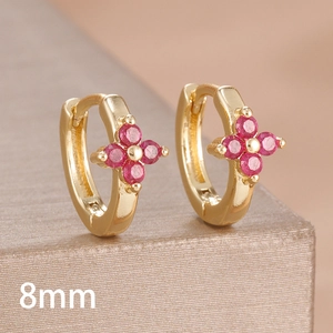 Macro detail of 8mm gold clover hoop earrings with vibrant red zircon stones
