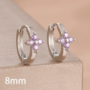 Macro shot of 8mm silver hoop earrings with purple zircon clover inlay on a jewelry box