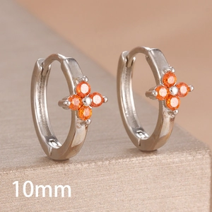 Macro detail of 10mm silver huggie earrings with orange zircon four-leaf clover design
