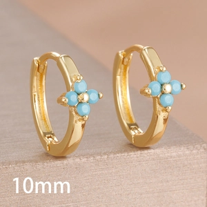 Macro view of 10mm gold hoop earrings with light blue zircon four-leaf clover design