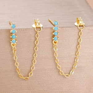 Detail of gold chain earrings with four light blue round beads in a U-shaped design