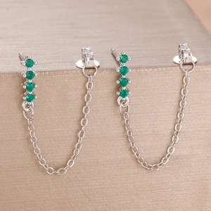 Macro shot of silver zircon drop earrings featuring four green stones and delicate O-chain