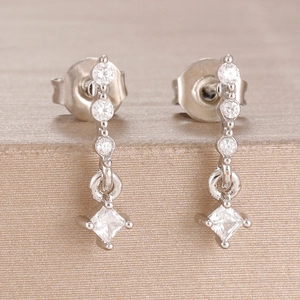 Detailed close-up of silver earrings featuring princess cut cubic zirconia stones