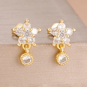 Macro shot of gold floral earrings with sparkling cubic zirconia crystals on gray display