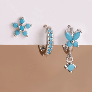 Detailed macro view of silver floral earrings with blue gems and a butterfly charm set