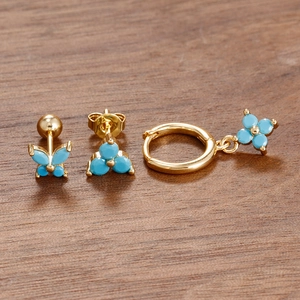 Detailed close-up of golden earrings set with blue butterfly and floral zircon designs