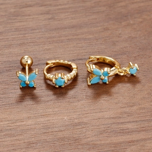 Macro view of three-piece gold earring set with blue butterfly and zircon stones