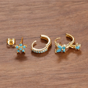 Macro shot of gold zircon flower earrings with blue stones on a dark wooden background