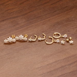 Vue détaillée de boucles d'oreilles fleurs dorées avec zircons sur un fond en bois