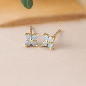 Detailed macro shot of light blue floral stud earrings with gold plating and zircons