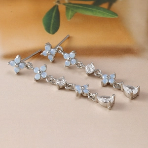 Detail of floral silver earrings with light blue opal stones and long zircon tassels
