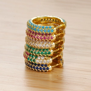 Set di sei paia di orecchini huggie dorati con zirconi colorati su superficie di legno