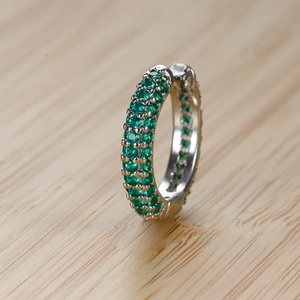 Dettaglio di orecchini huggie in argento con tre file di pietre di zirconia verdi