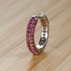 Dettaglio macro di orecchini a cerchio in argento con zirconi magenta micro-incastonati