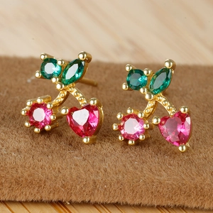 Macro detail of cherry stud earrings with 18K gold plating and red heart-shaped crystals